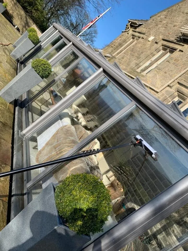 Water-fed pole cleaning a grey conservatory